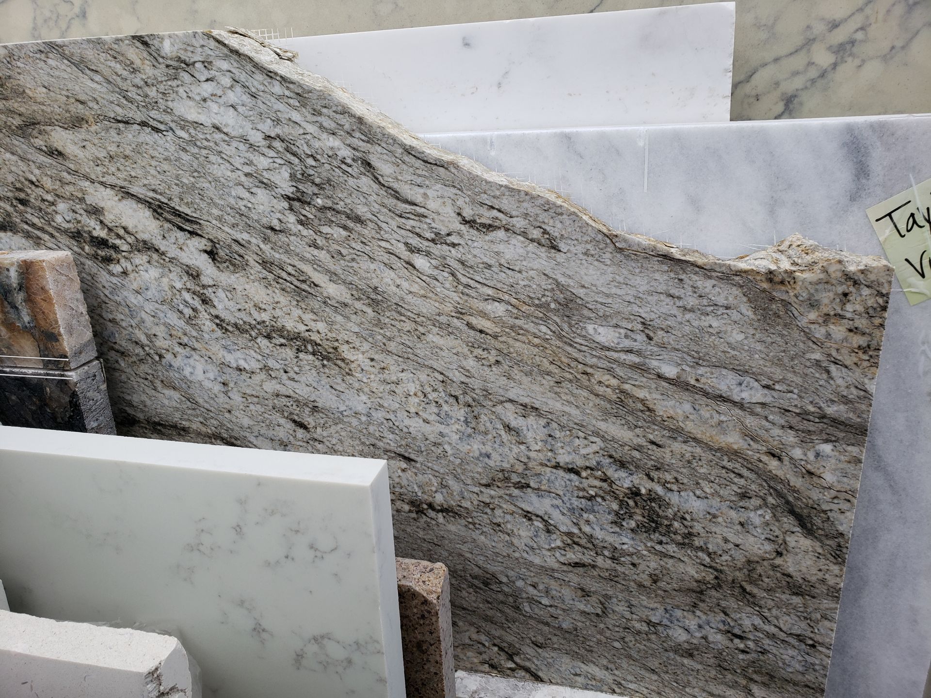 Stacked marble slabs in gray and white, likely in a stone yard or showroom.