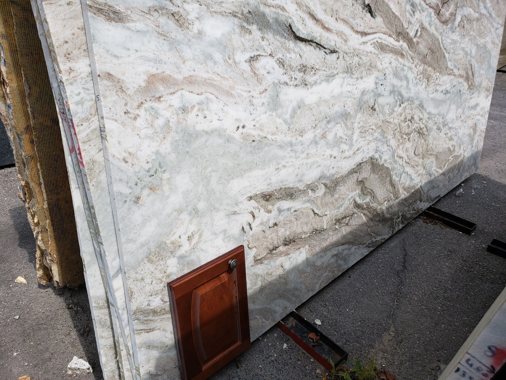 Marble slab leaning against a wall beside a small brown panel on the ground