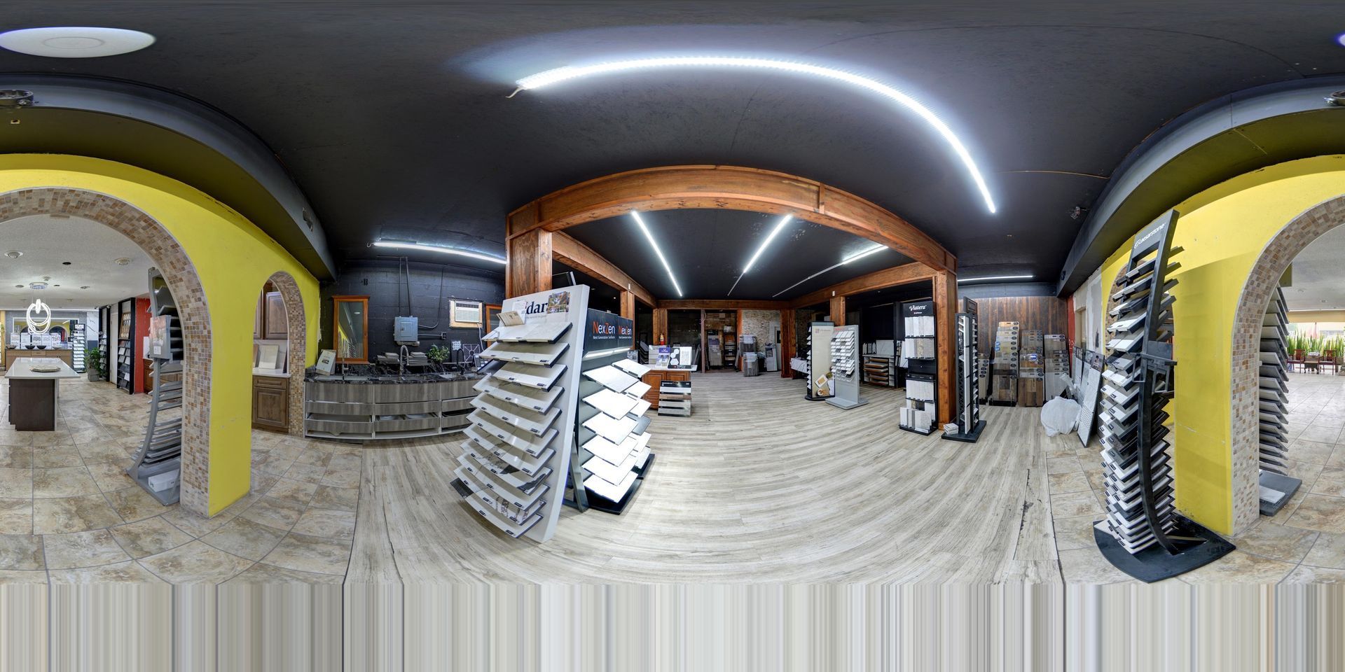 Wide-angle interior of a tiled shop or market with shelves, arches, and stacked chairs under curved ceiling lights