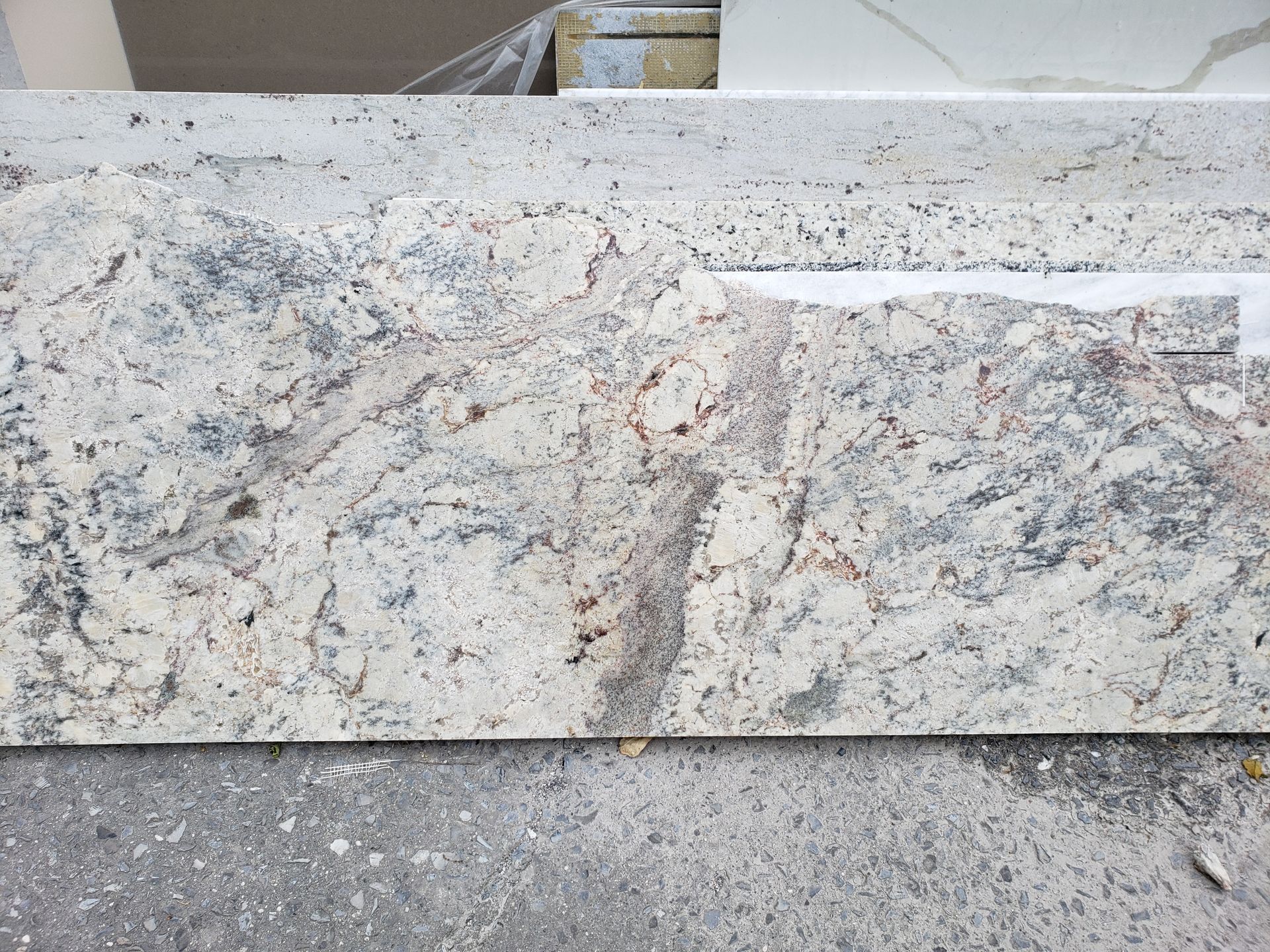 Light gray and speckled stone block with a rough concrete surface behind it.