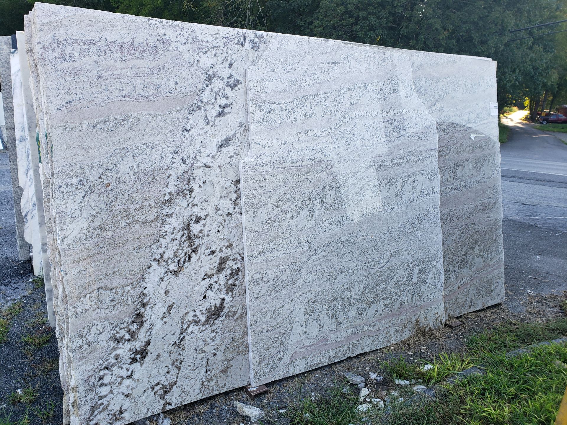Large white stone monument blocks beside a road, with grass and trees in the background
