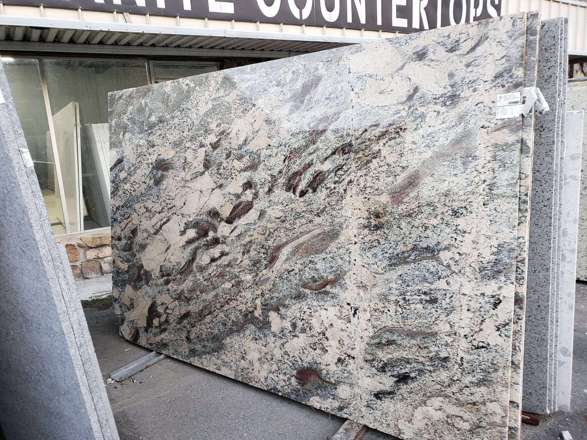Large white-and-gray speckled granite countertop slab displayed in a stone showroom