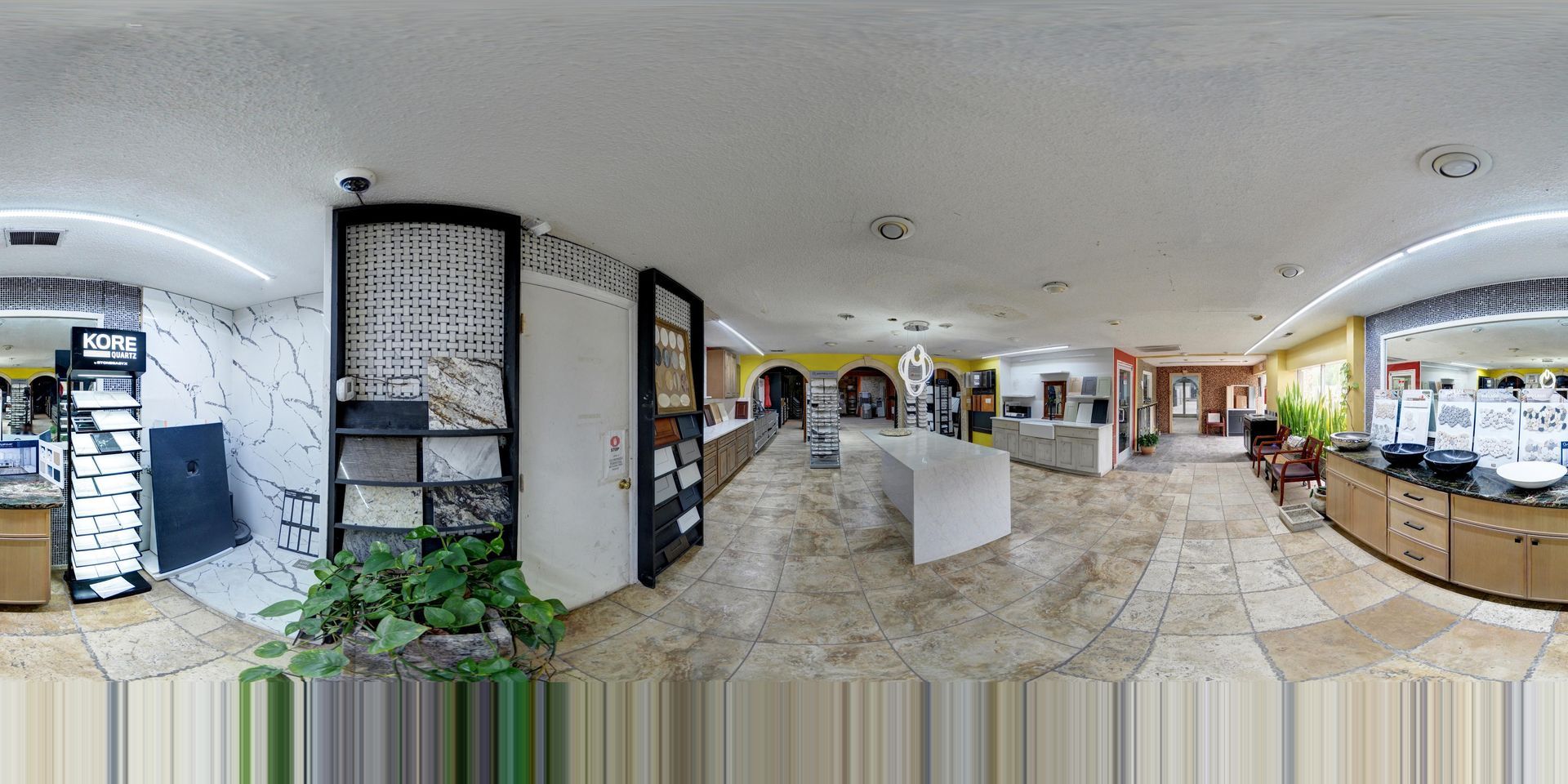 Bright lobby with display cases, potted plants, and a central white counter in a modern building