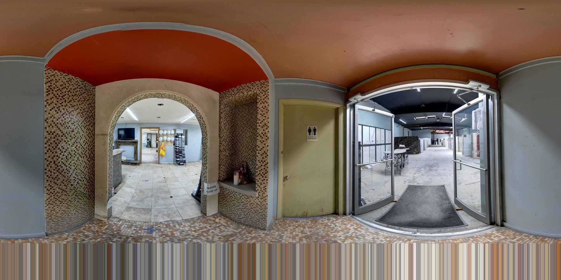 Panoramic view of a covered building walkway with tiled walls and a snowy entrance outside.