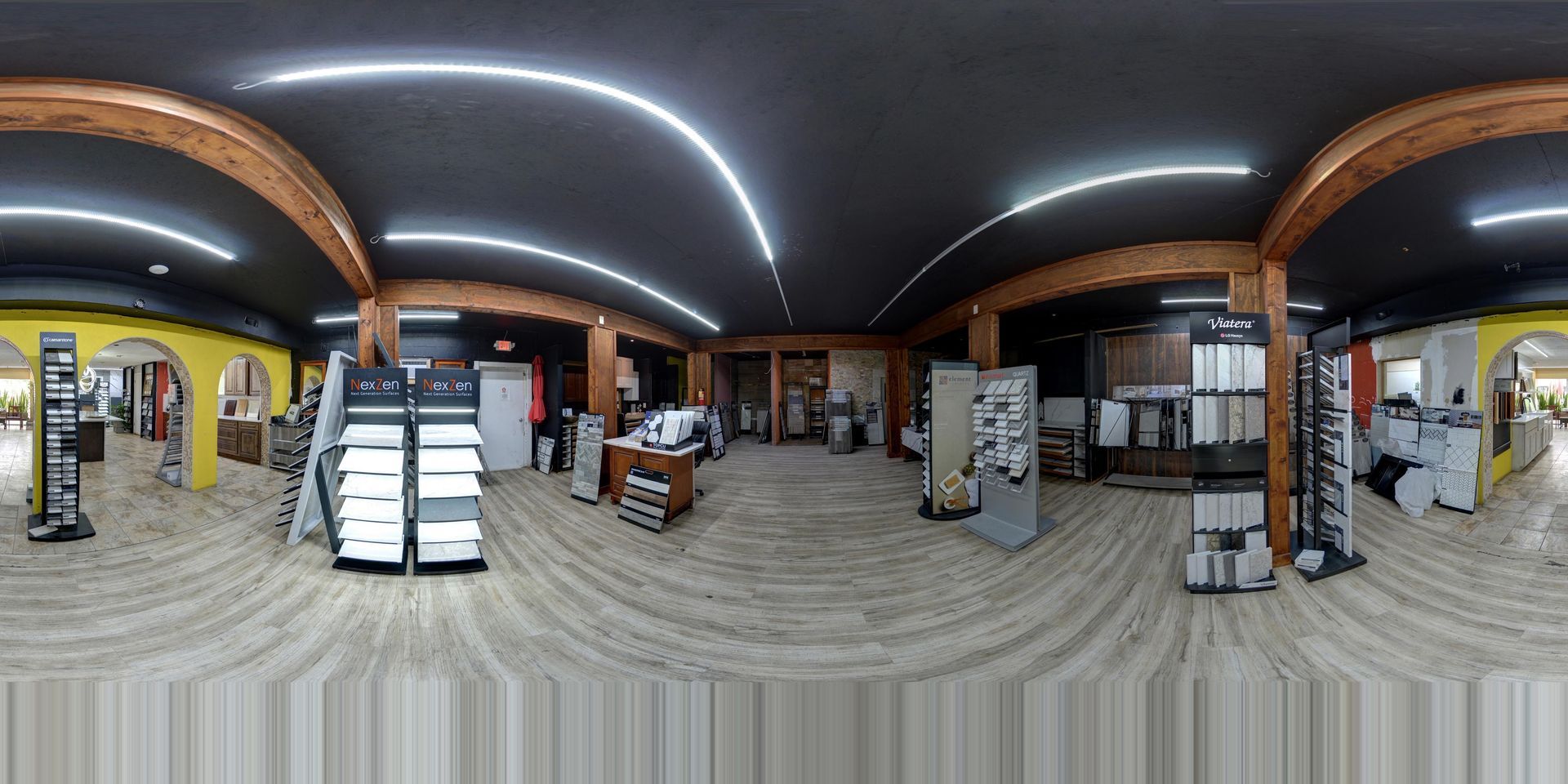 Wide indoor retail store with shelves, display racks, and warm ceiling lights; a few people in the background
