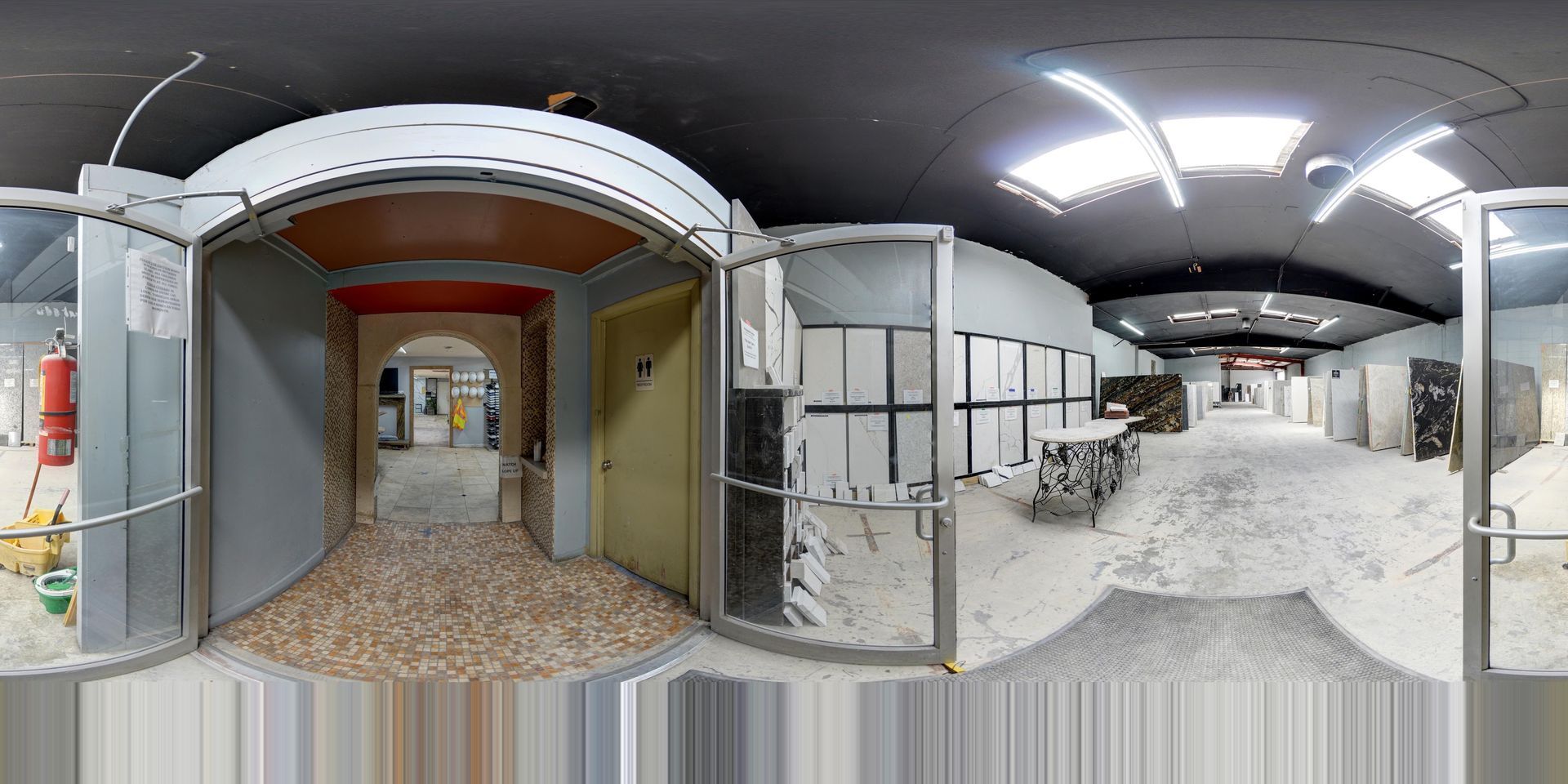 Abandoned hallway under renovation with exposed walls, white debris, and a lit corridor extending ahead