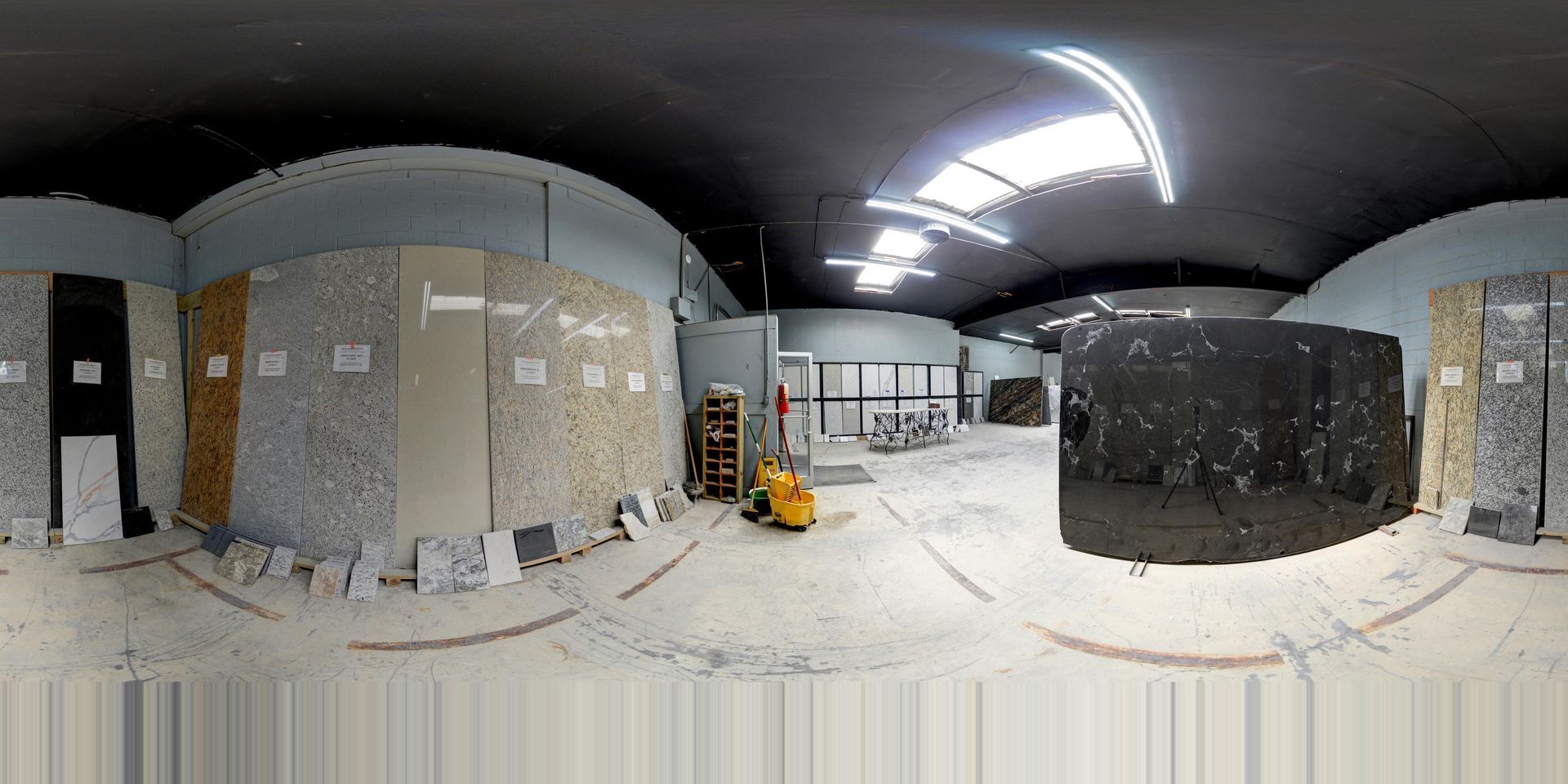 Panoramic view of a dusty industrial room with cabinets, equipment, and overhead lights.