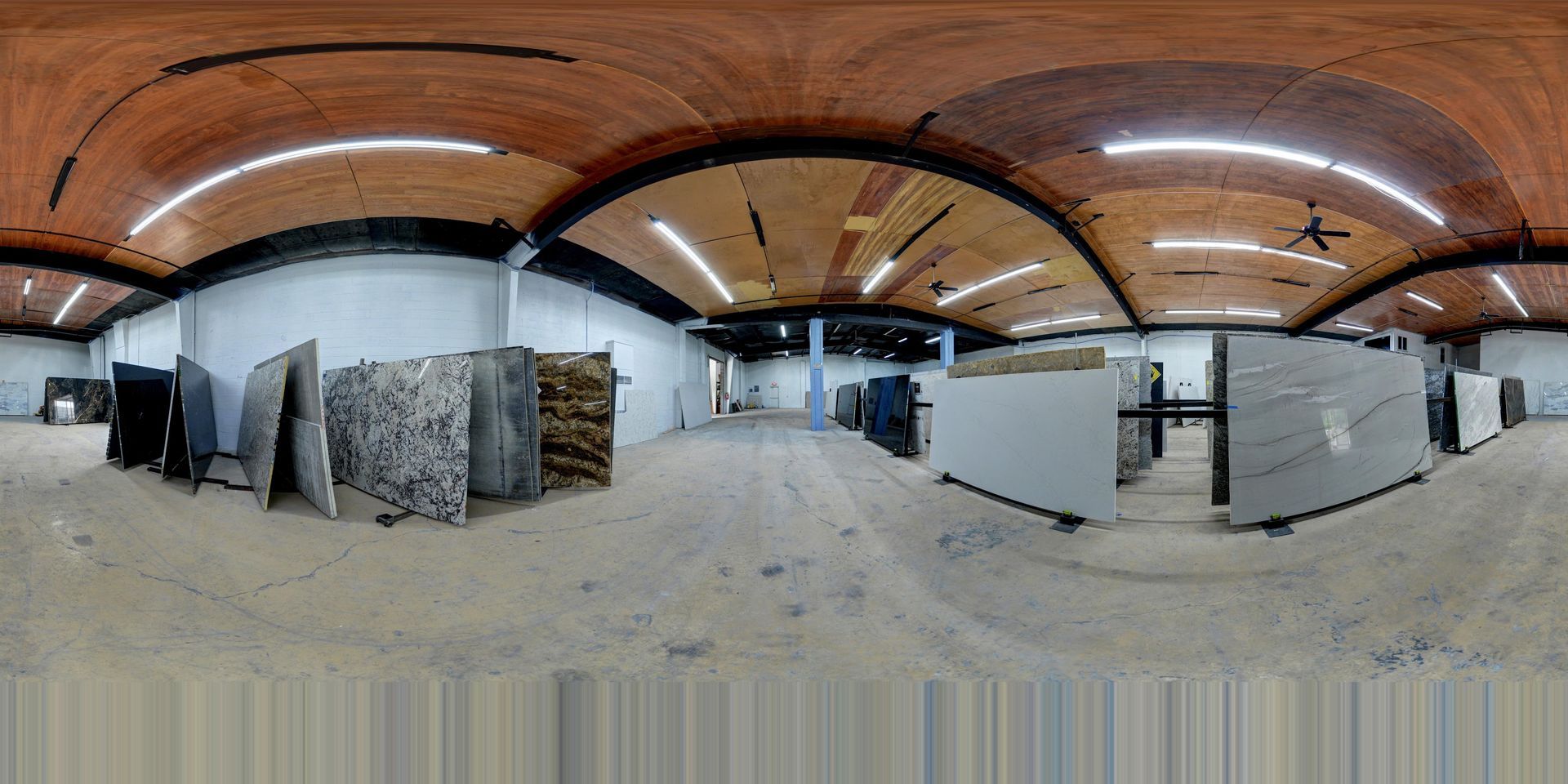 Wide-angle view of an empty industrial warehouse with stacked materials and white partitions under arched wooden ceilings