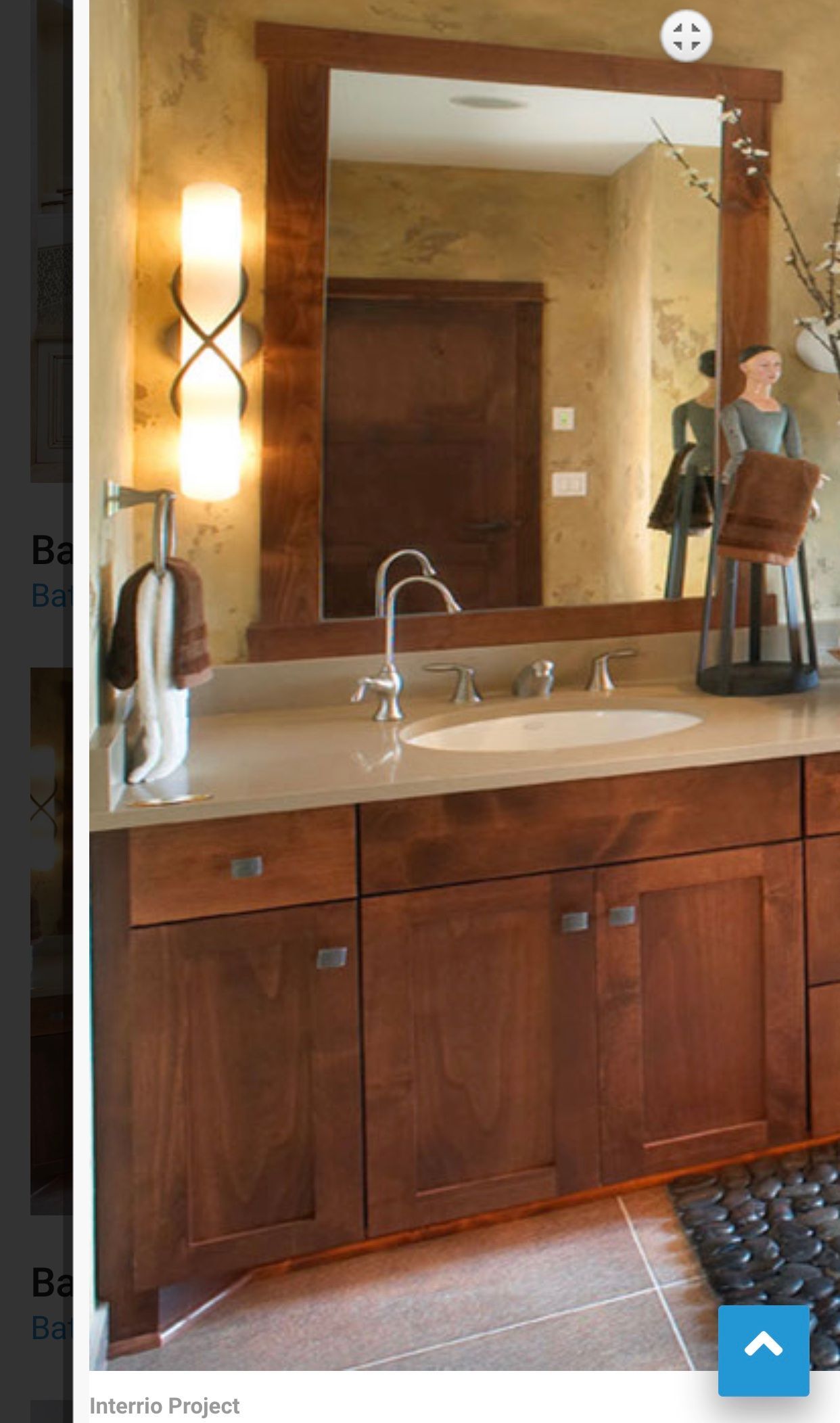 Wood vanity bathroom sink with large mirror, wall sconces, and dark wood cabinets