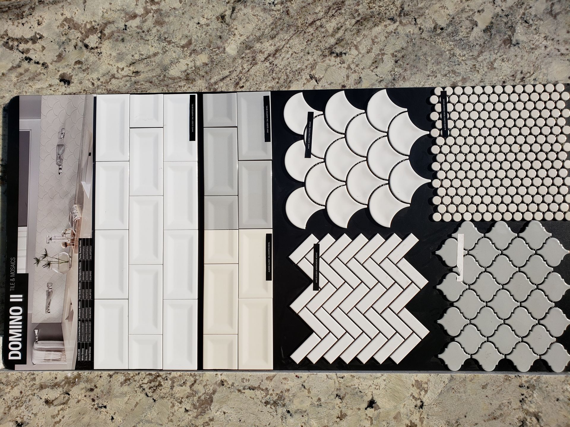 Tile sample board with white, gray, and black patterned tiles in varied geometric designs