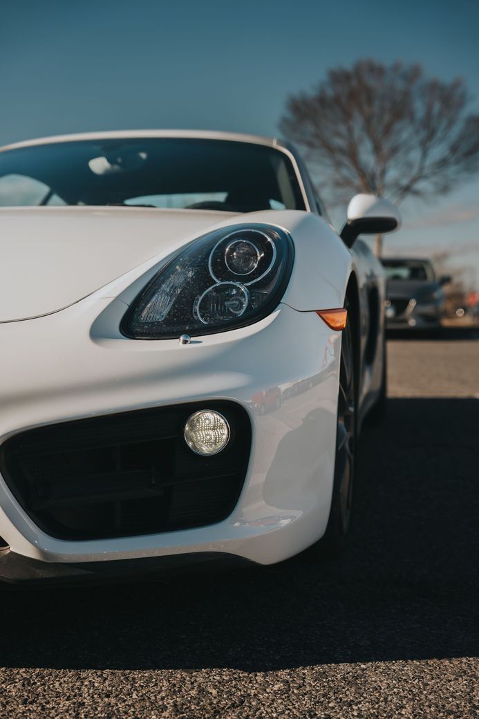 White sports car front end parked outdoors on a sunny day