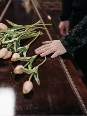 Hand arranging tulips on a dark wooden table