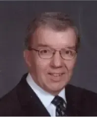 Portrait of a man in a suit and glasses against a gray background
