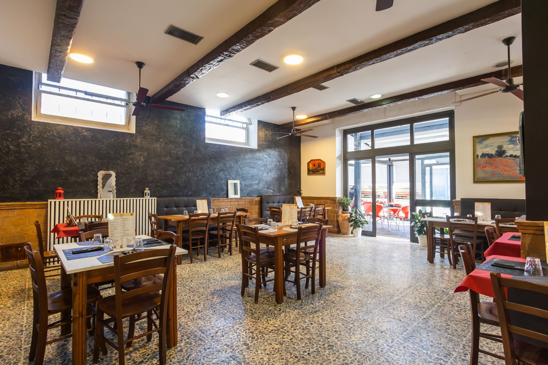 Sala da pranzo tranquilla del ristorante con tavoli e sedie in legno e ampie finestre che lasciano entrare la luce naturale.