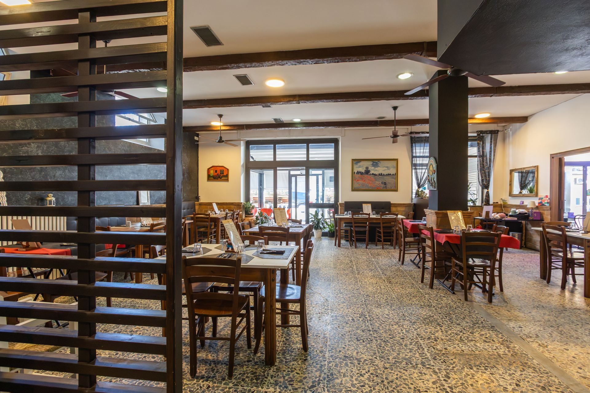 Luminosa sala da pranzo del ristorante con tavoli e sedie in legno e una scala in primo piano.