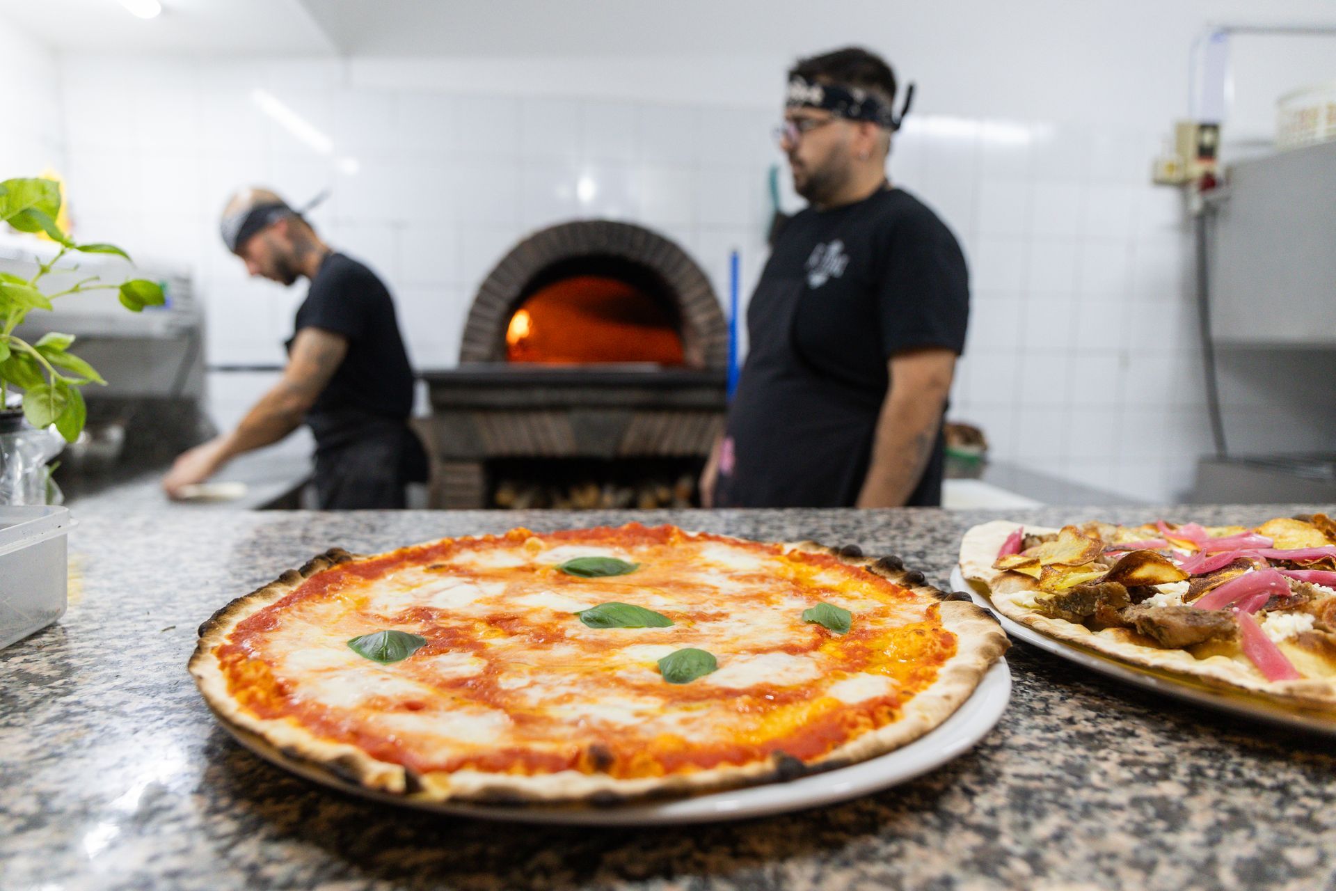 Chef in una pizzeria con forno a legna e pizze sul bancone