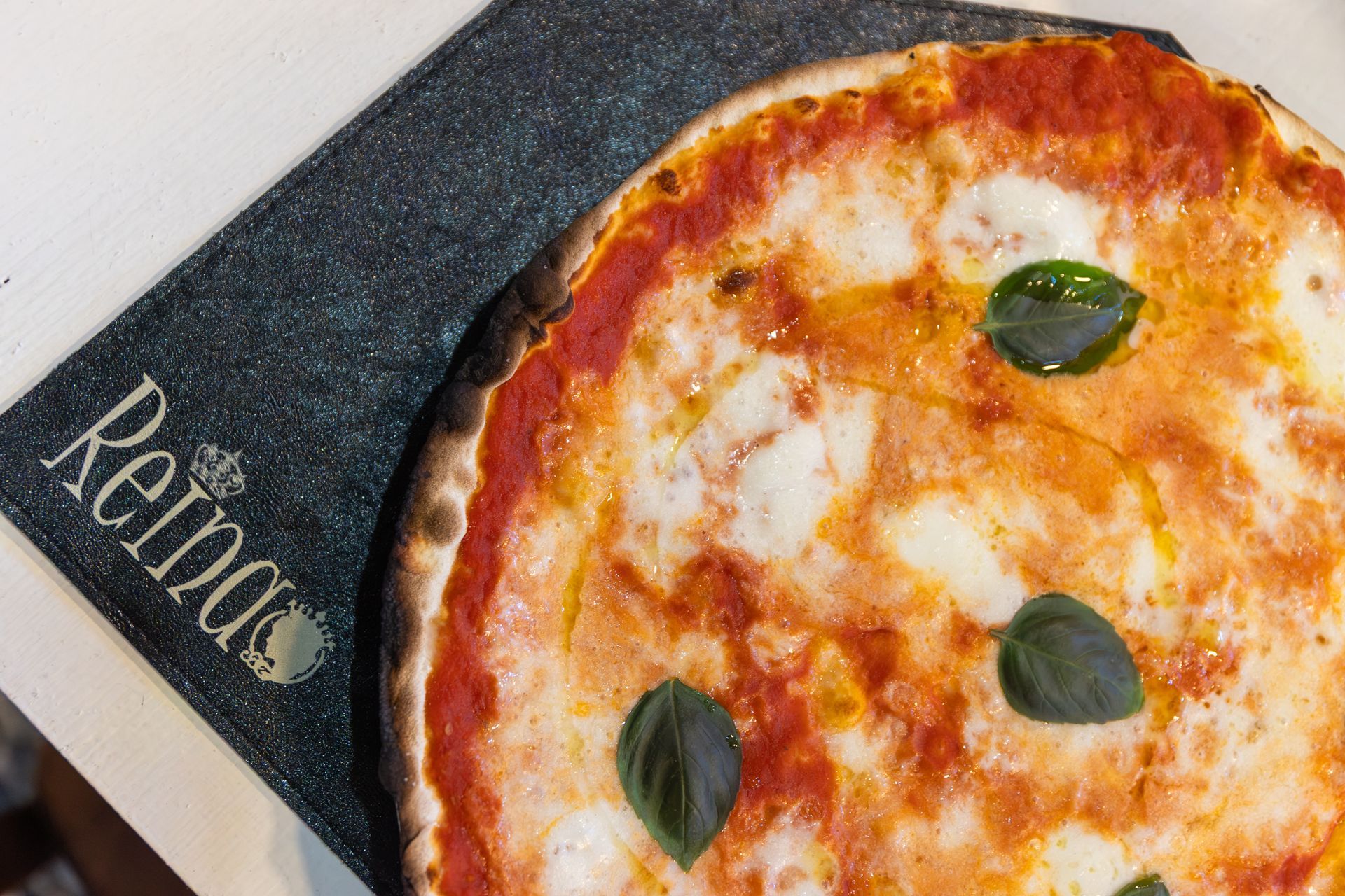 Pizza Margherita su un tagliere scuro con la scritta “Rabbio” ben visibile