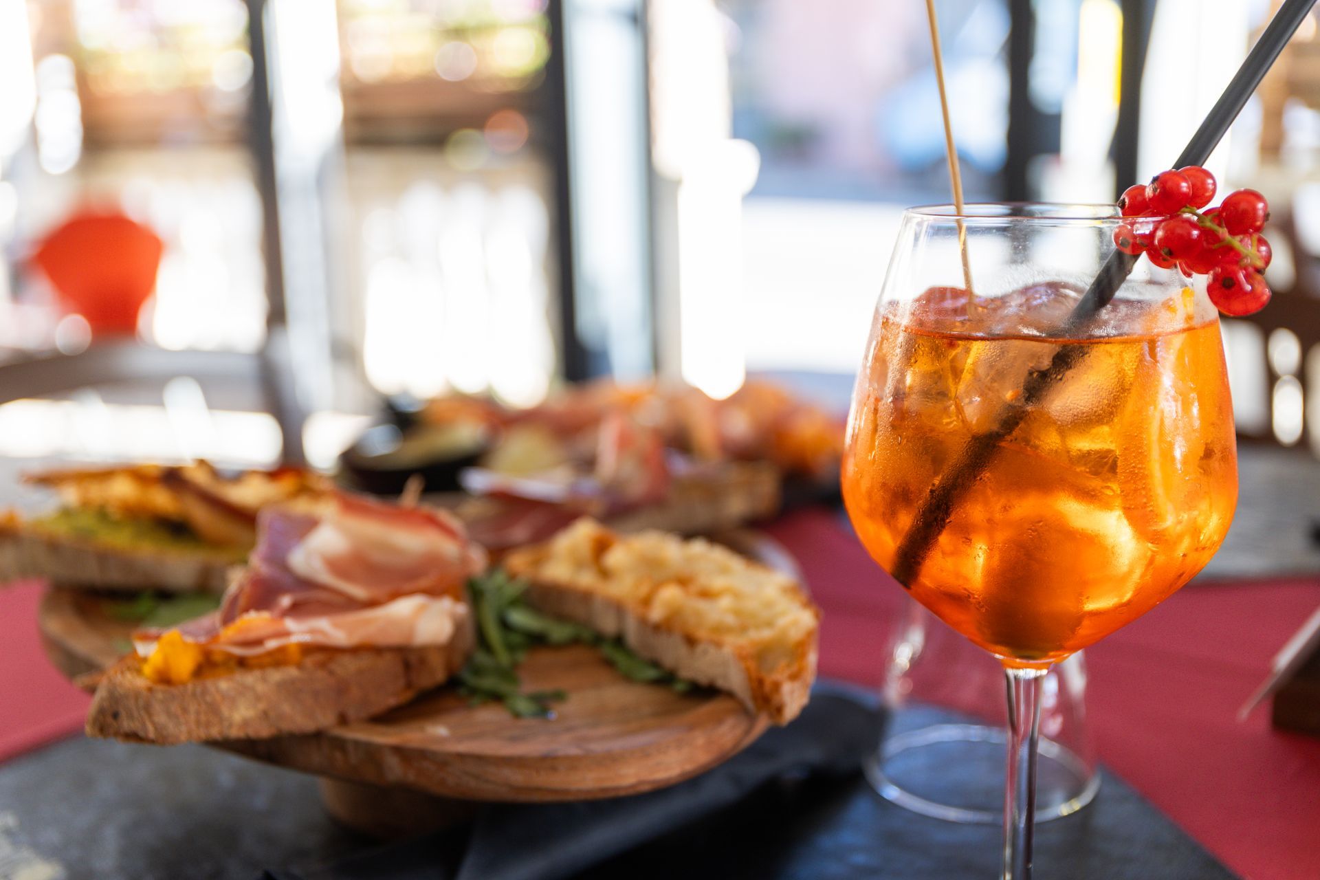 Cocktail con frutti rossi accanto a tramezzini su un tavolo del ristorante.