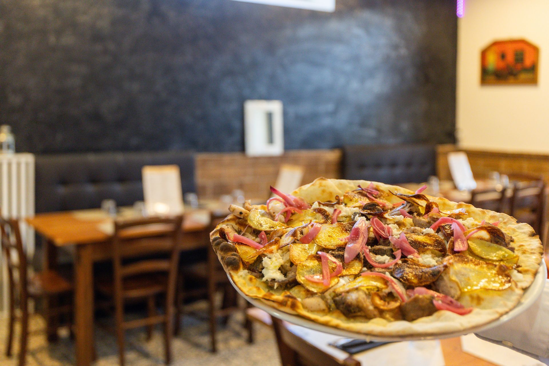 Una fetta di pizza su un piatto in un accogliente ristorante con tavoli e sedie in legno.