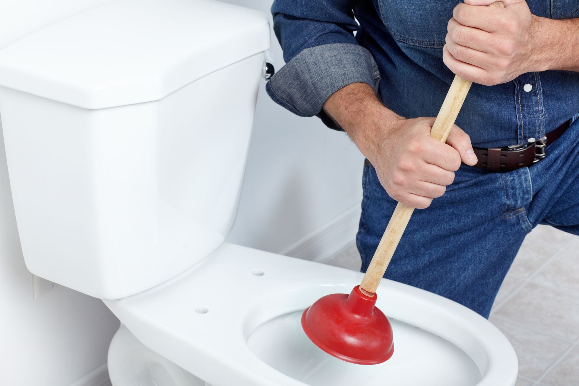 A man is using a plunger to unblock a toilet