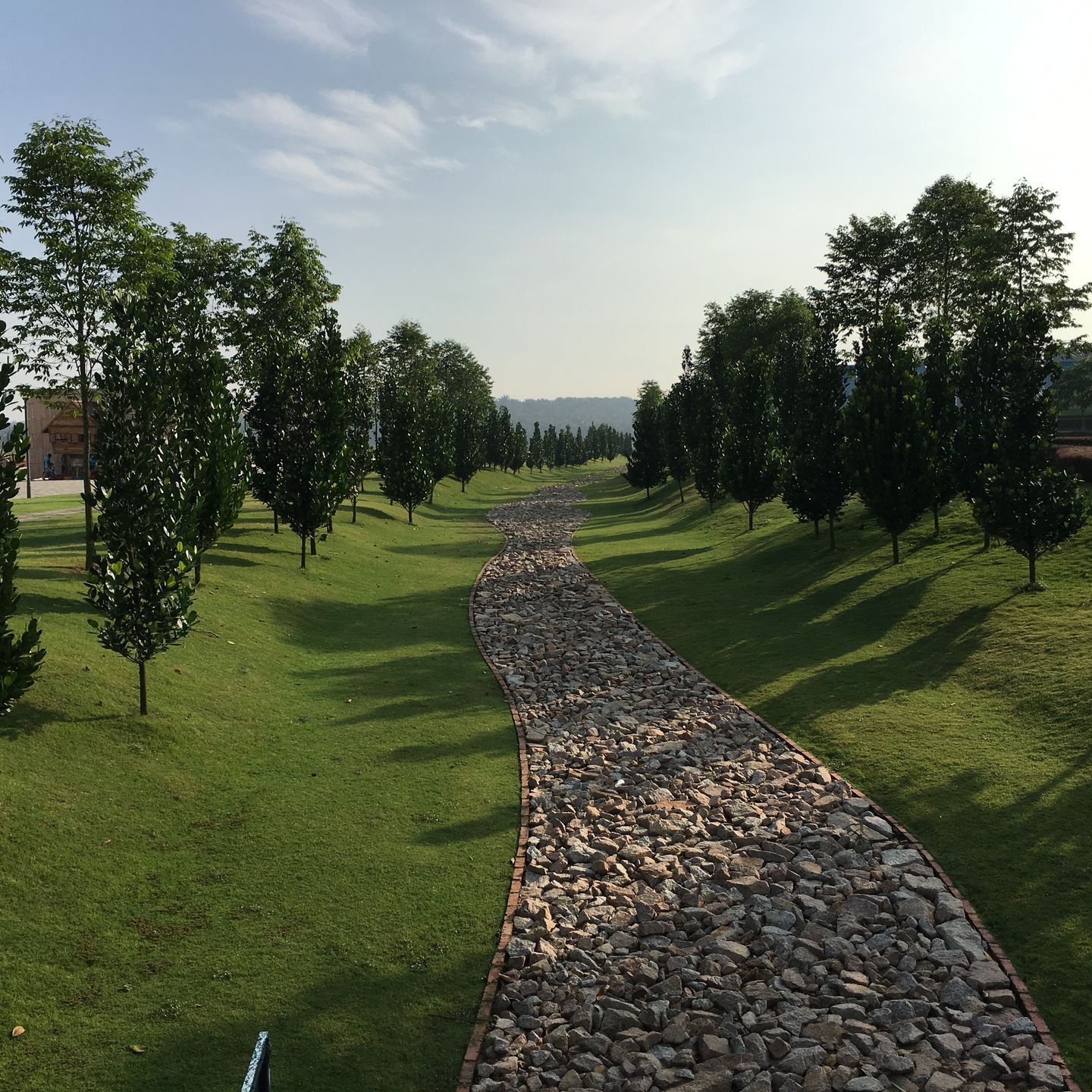 A stone path in a park with trees on both sides
