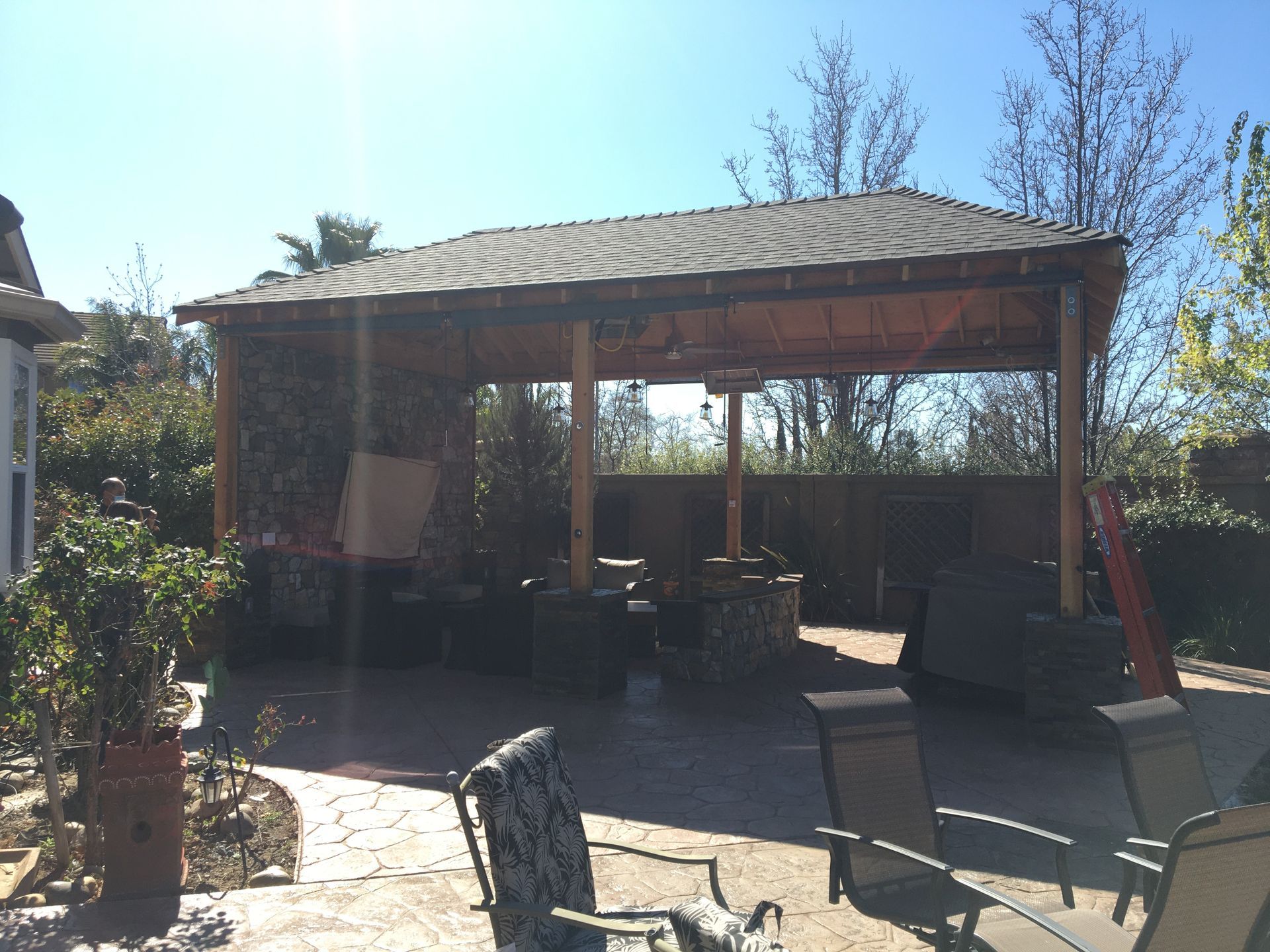Patio with covered gazebo, outdoor seating, and potted plants in bright sunlight