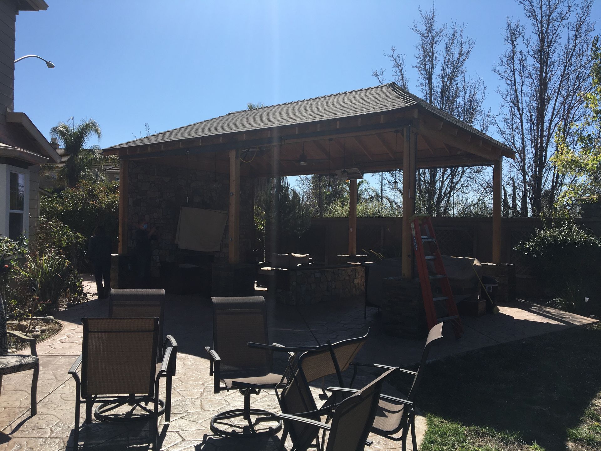Covered patio with outdoor chairs and tables in a sunny backyard