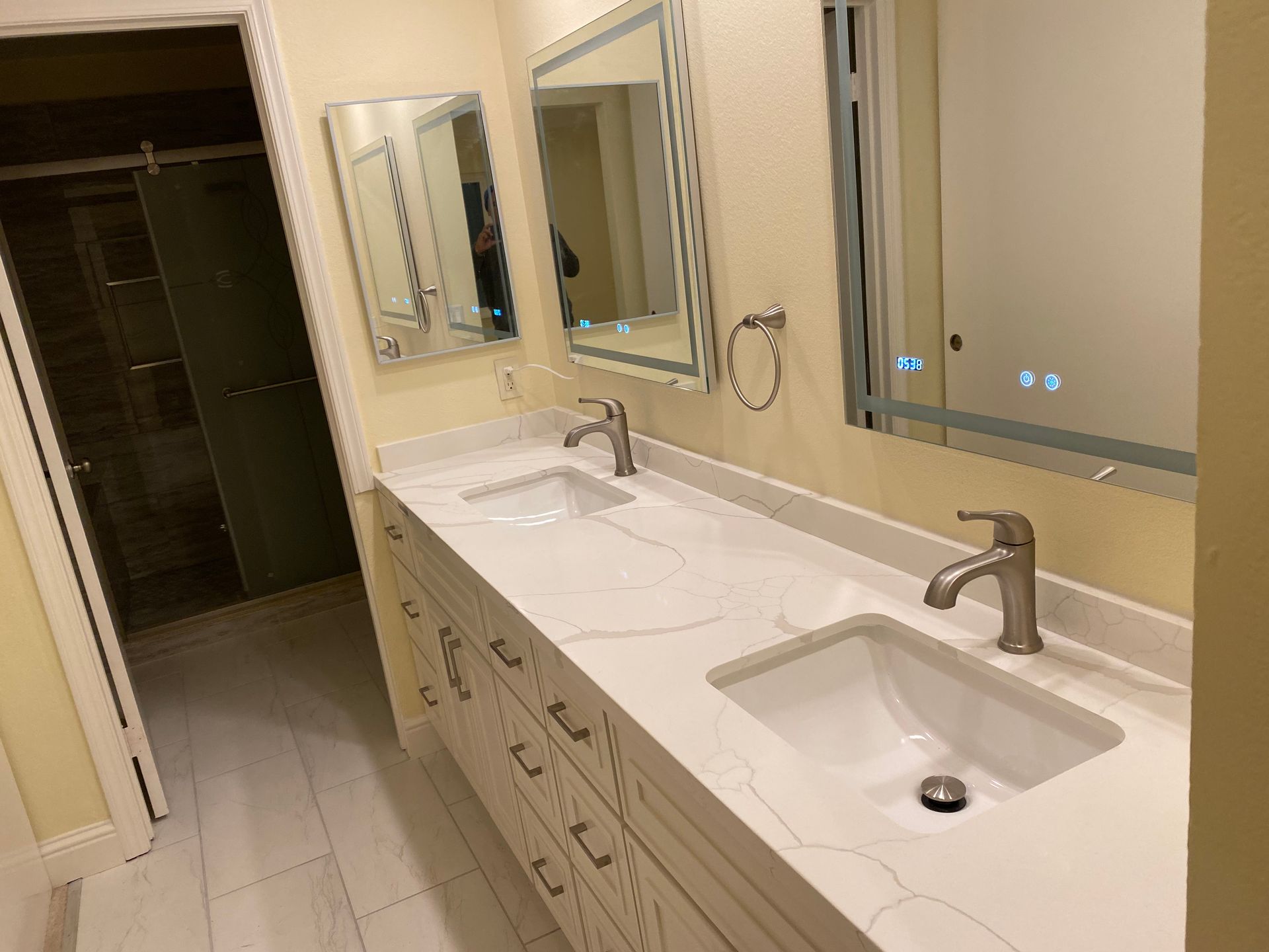 Bathroom vanity with two sinks, mirrors, and beige walls in a hallway-style room