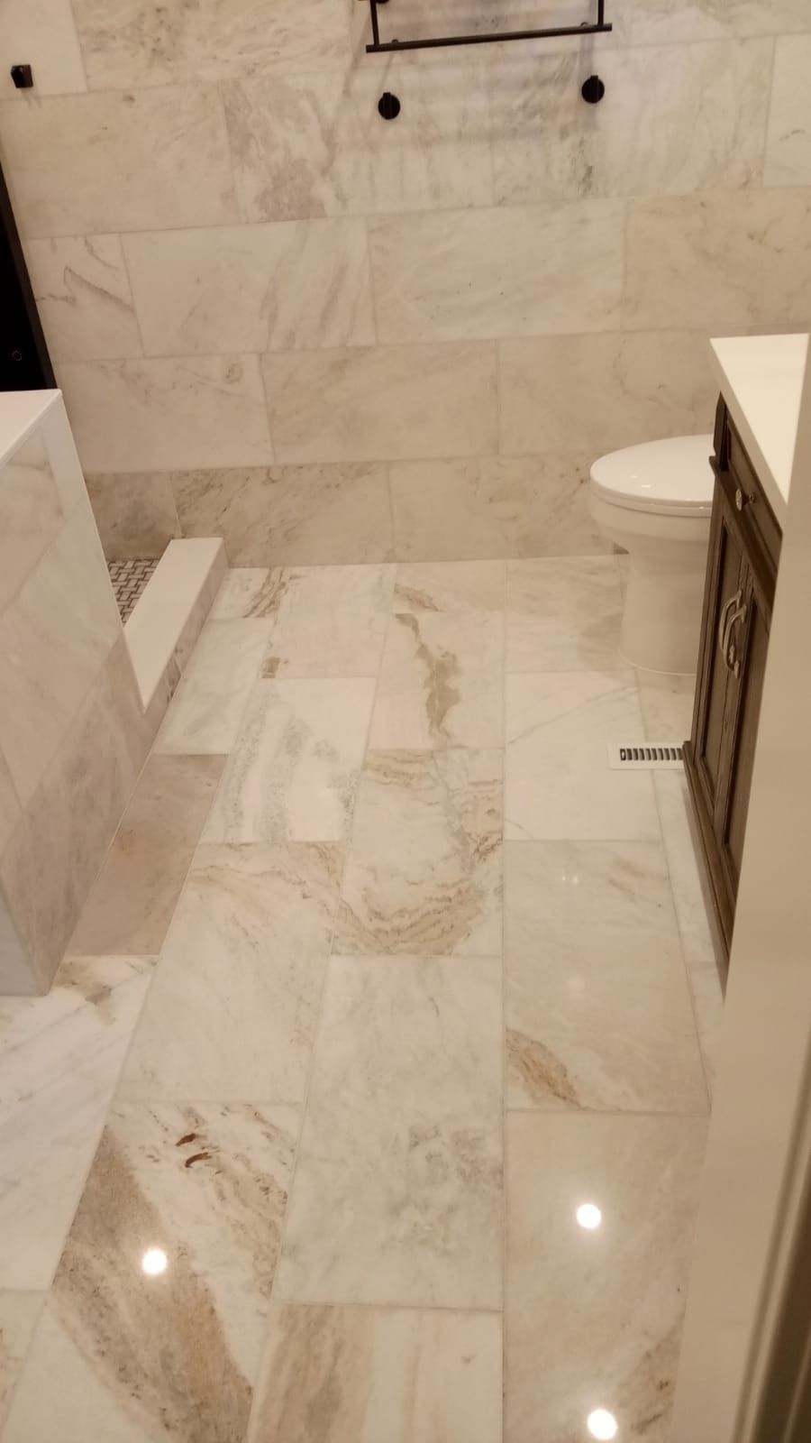 Small tiled bathroom with a walk-in shower, wall-mounted toilet, and vanity on the right.