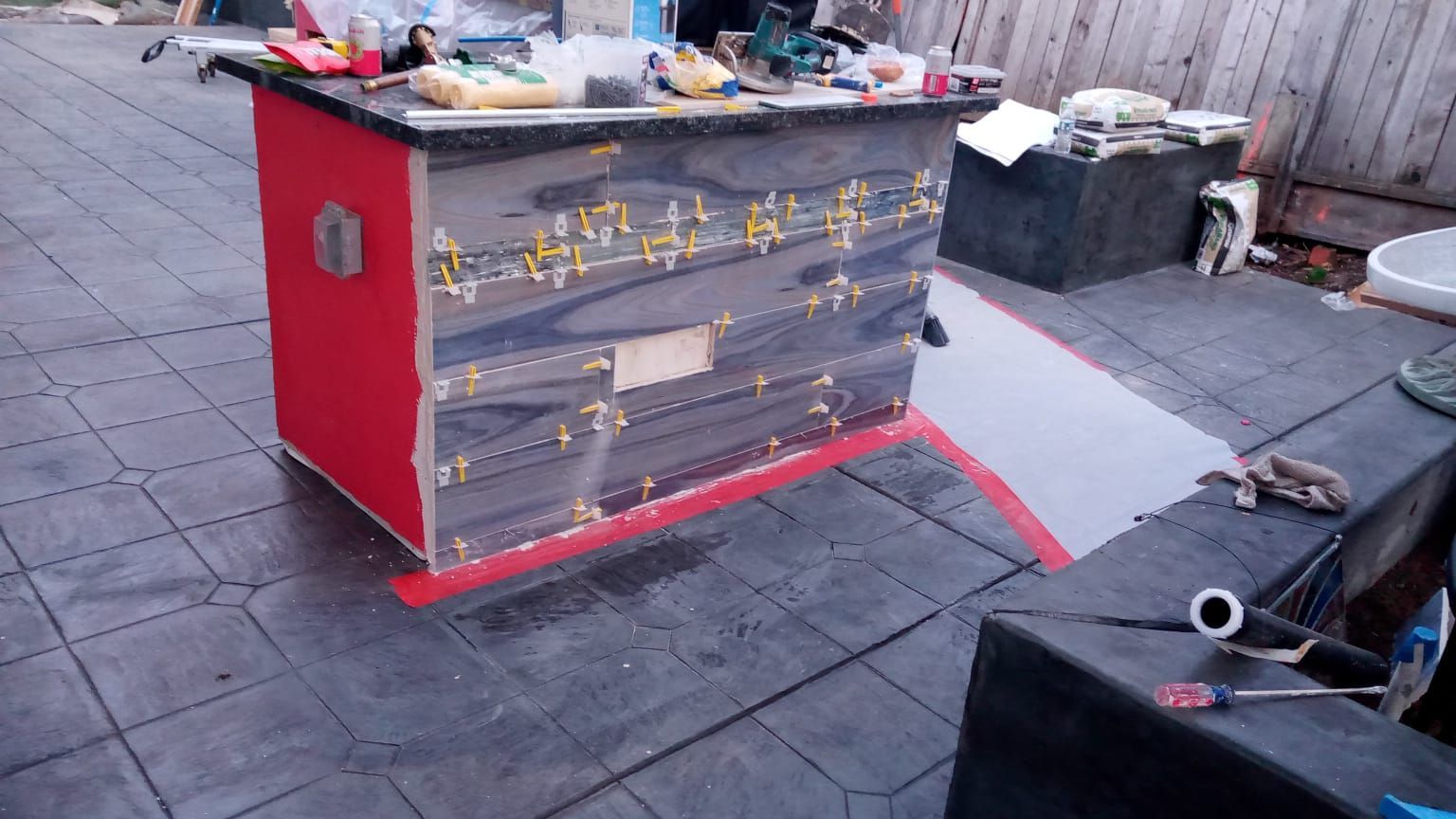 Red and gray street vendor cart covered in graffiti on a paved sidewalk with scattered items around it