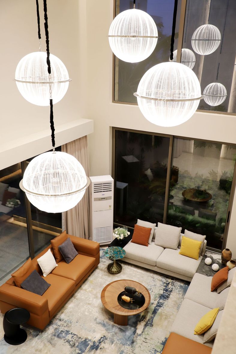 Modern living room with orange and white sofas, round coffee table, and hanging globe lights