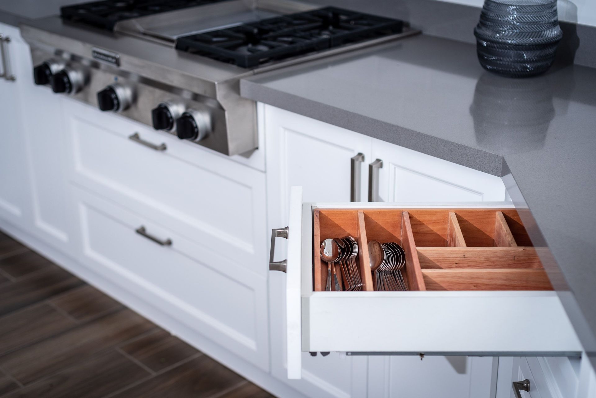 Modern kitchen with a stove and an open drawer showing organized utensils and spices