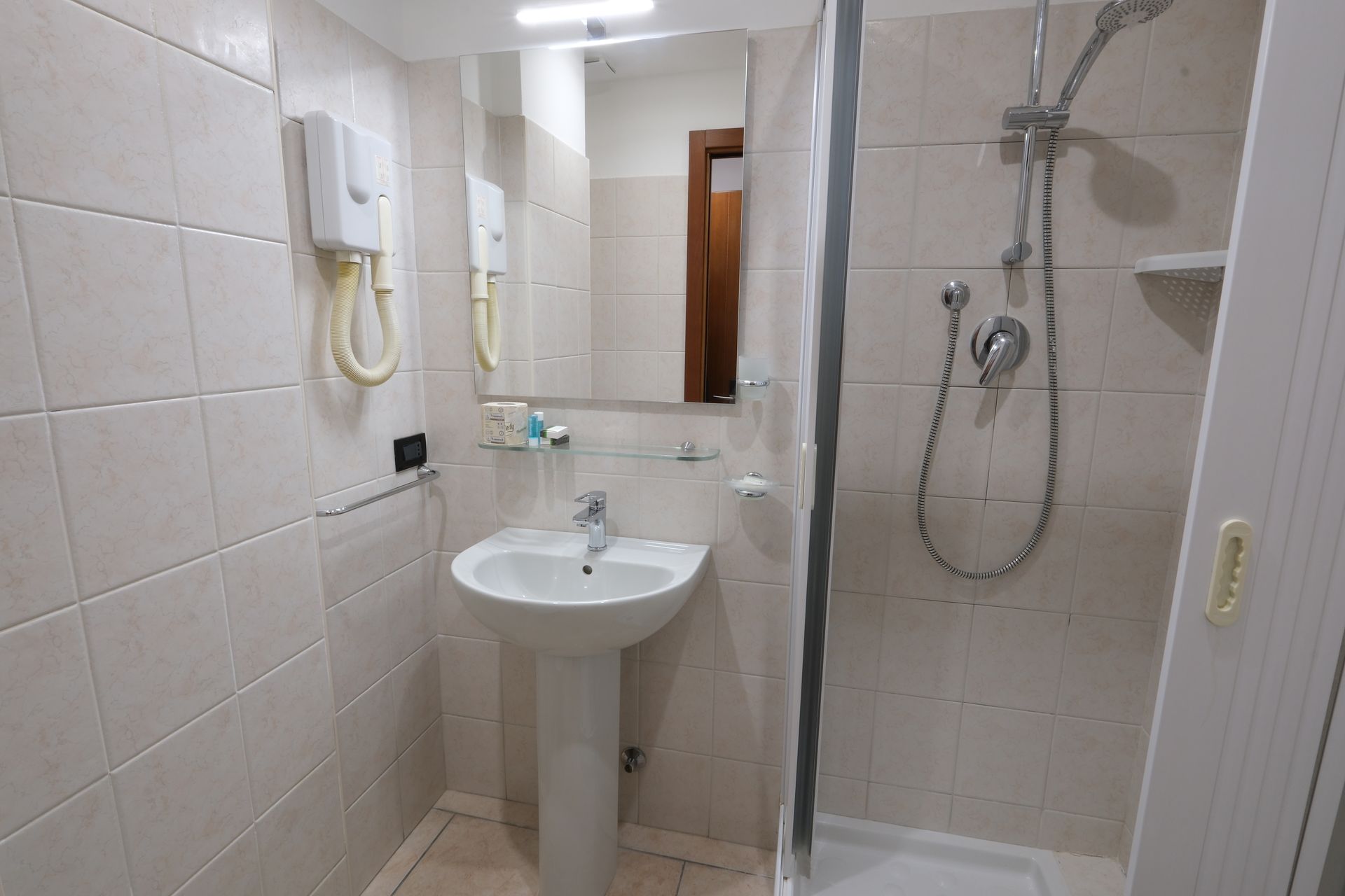A bathroom with a sink , shower and mirror.