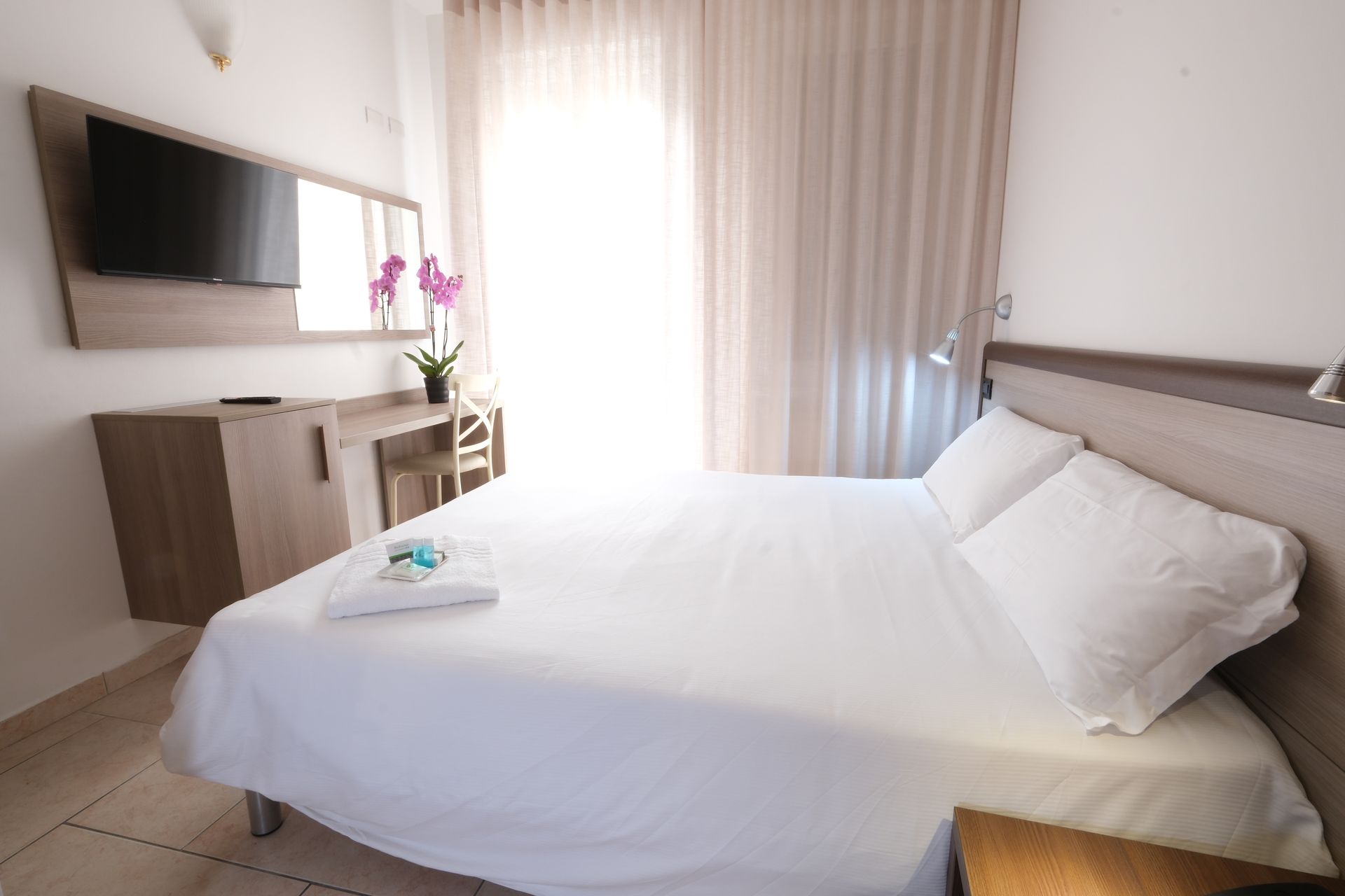 A hotel room with a king size bed and a flat screen tv.