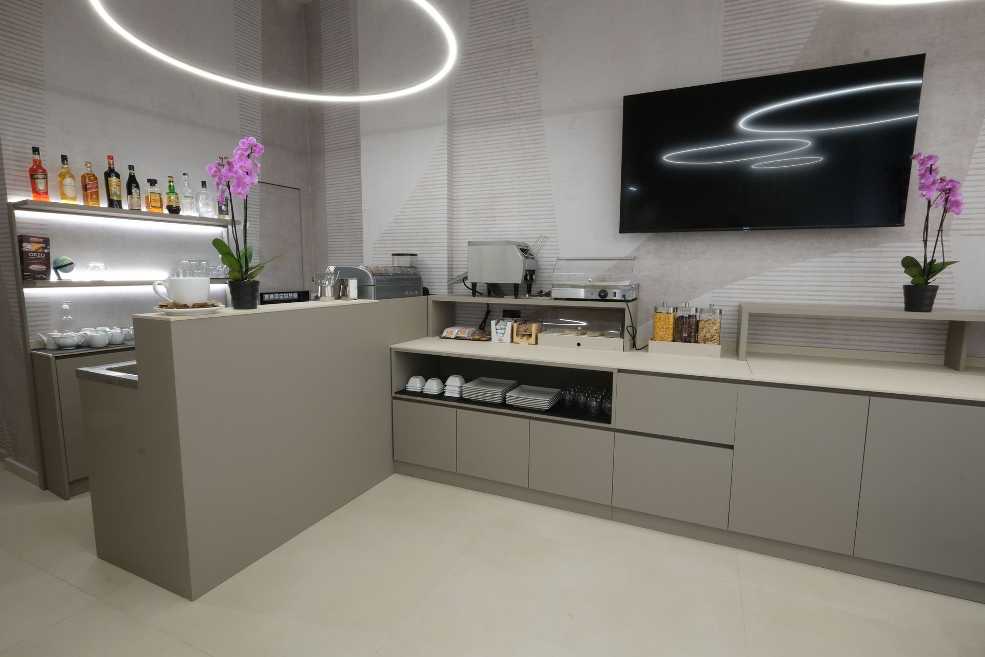 A kitchen with a bar and a flat screen tv on the wall.