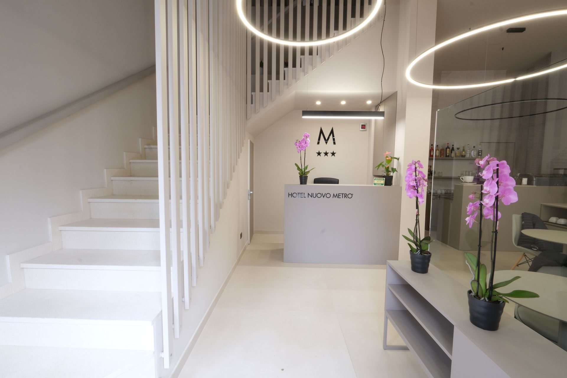 A lobby with stairs and a reception desk with the letter m on it