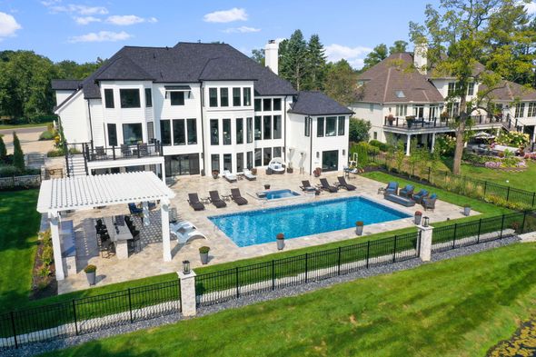Luxury white mansion with a blue swimming pool and patio in a fenced landscaped yard