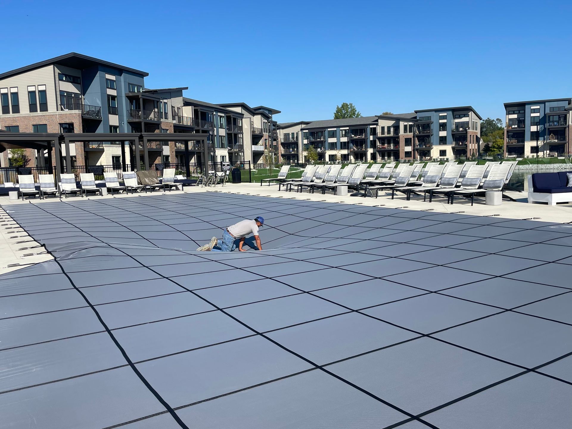 Child crawling on a large outdoor tiled play area at a modern apartment complex under a clear blue sky