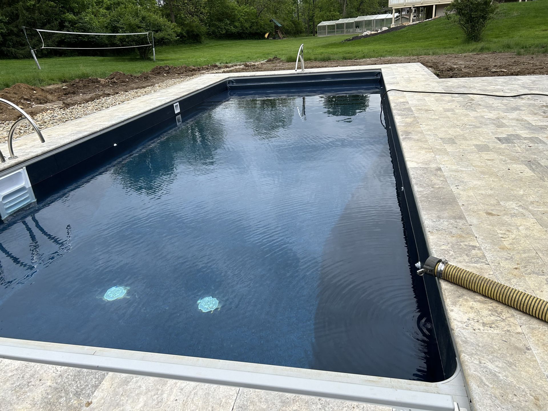 Rectangular outdoor pool with dark blue water beside a concrete deck and grassy yard