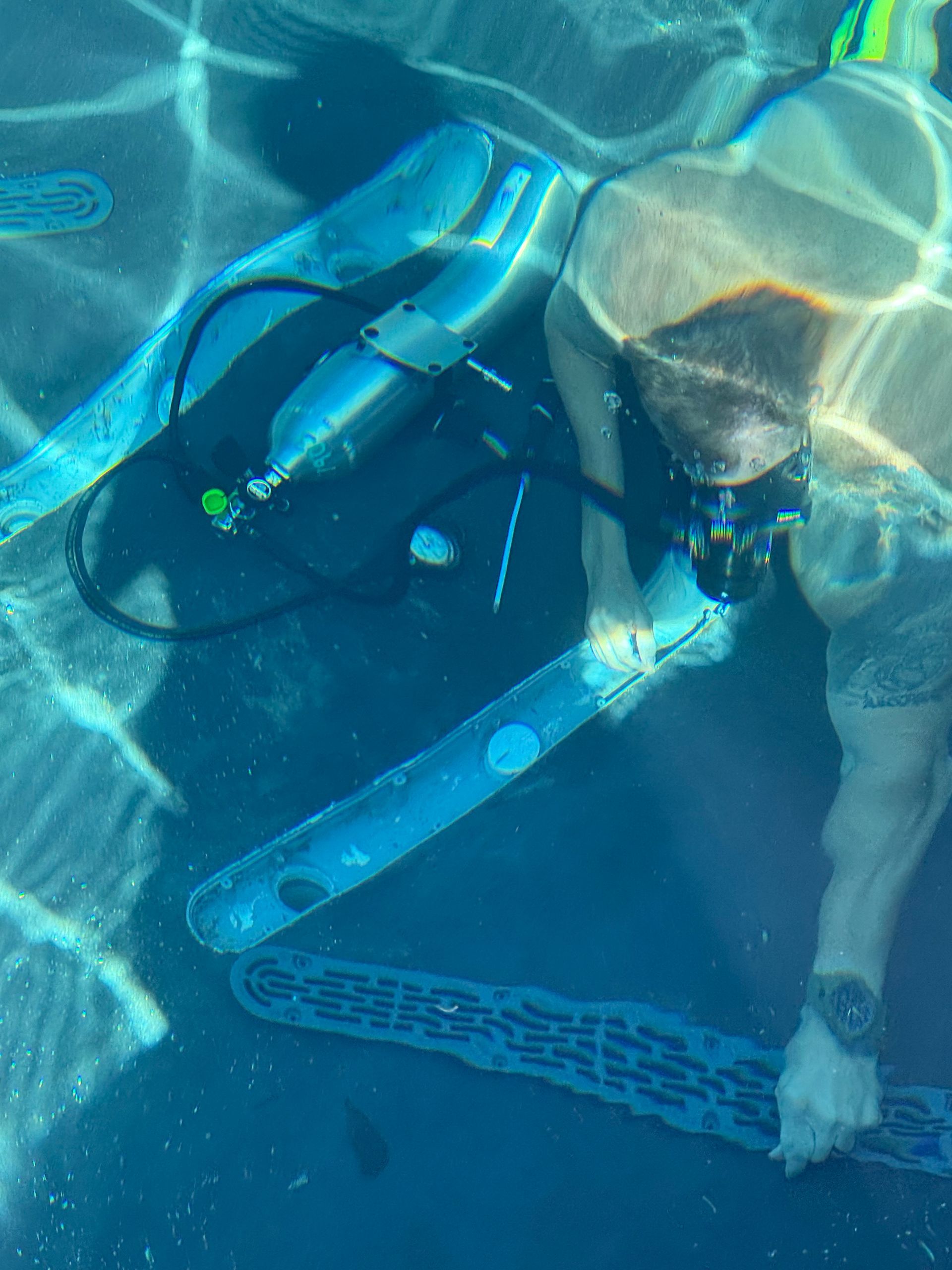 Person snorkeling underwater with a blue diving mask and fins in a swimming pool
