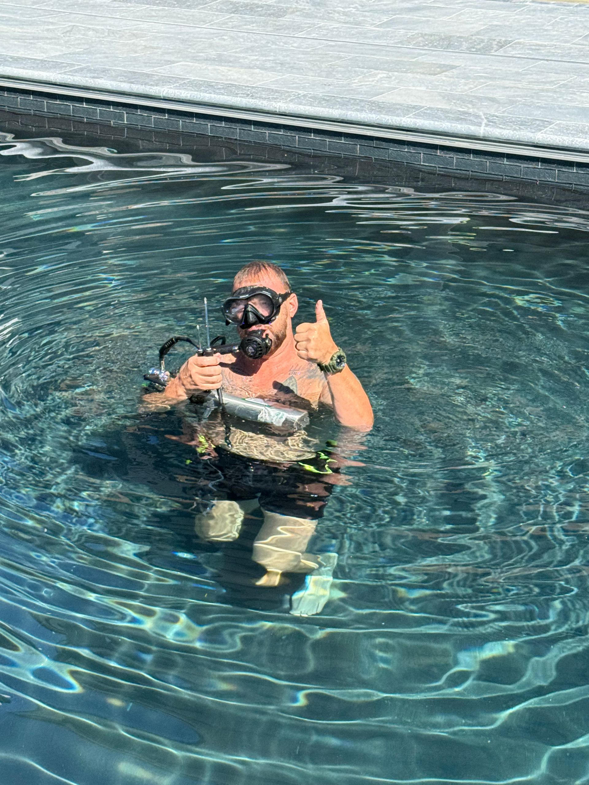 Person floating in a pool, wearing snorkel gear and giving a thumbs-up.