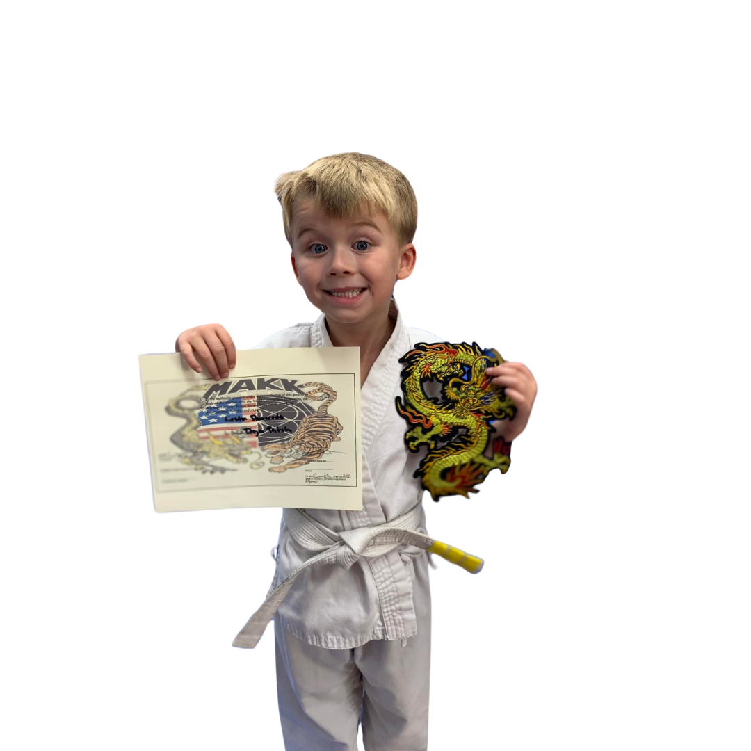 A boy and two girls are wearing karate uniforms and pointing at the camera