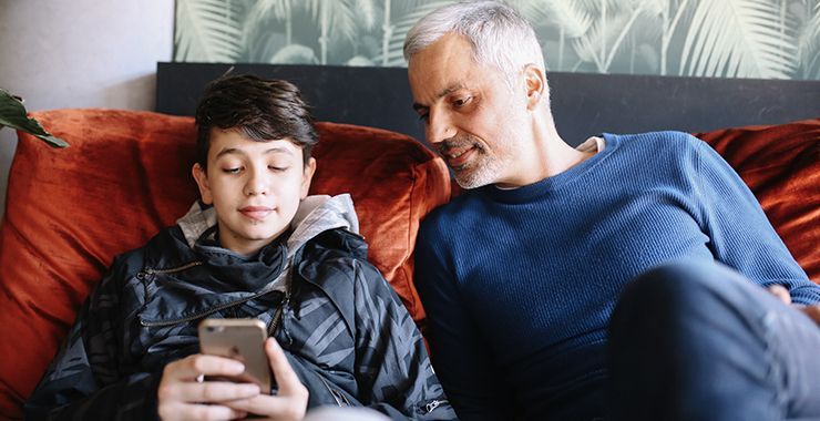 Father and son looking at son's phone