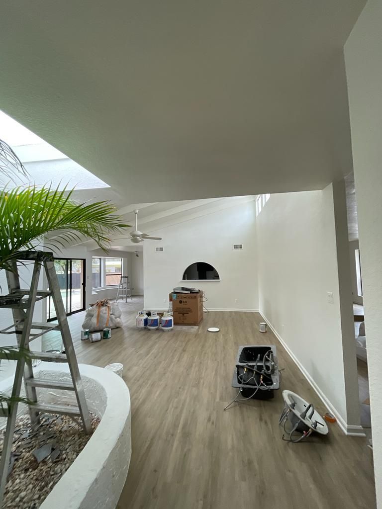 Interior of a renovated home with white walls, skylight, and new flooring; ladder and equipment present.