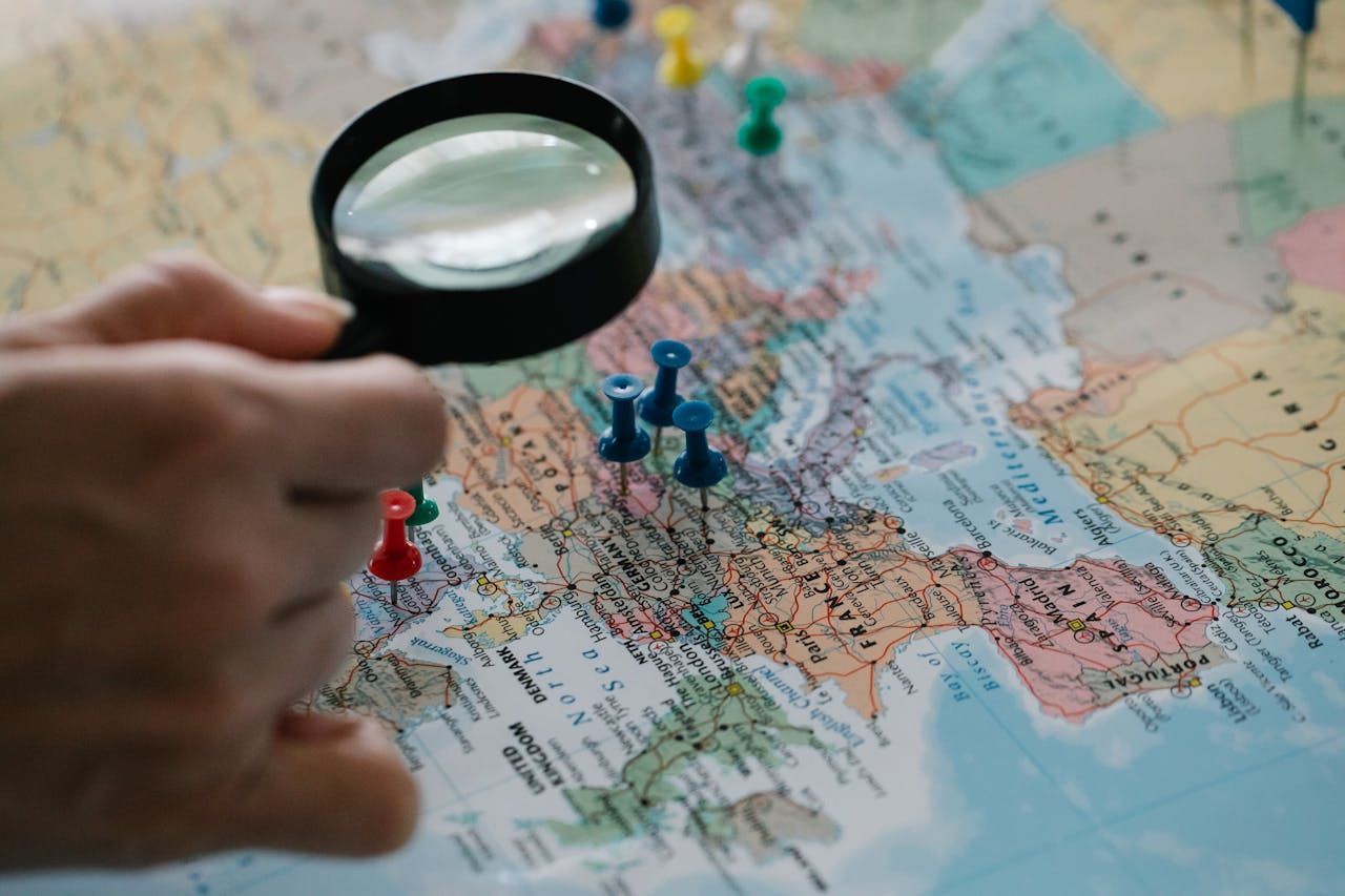 A person is holding a magnifying glass over a map of the world.