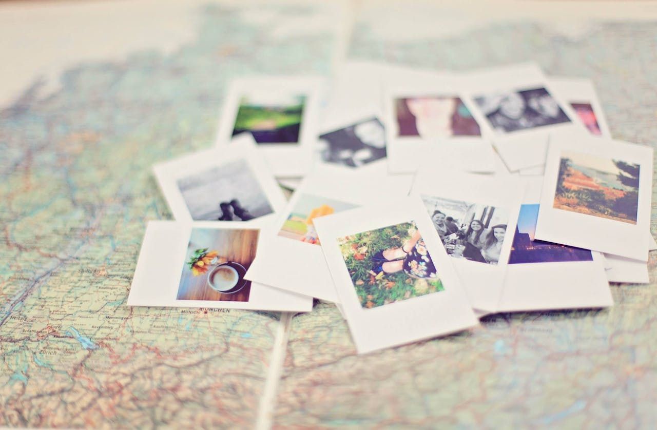 A pile of polaroid pictures sitting on top of a map.