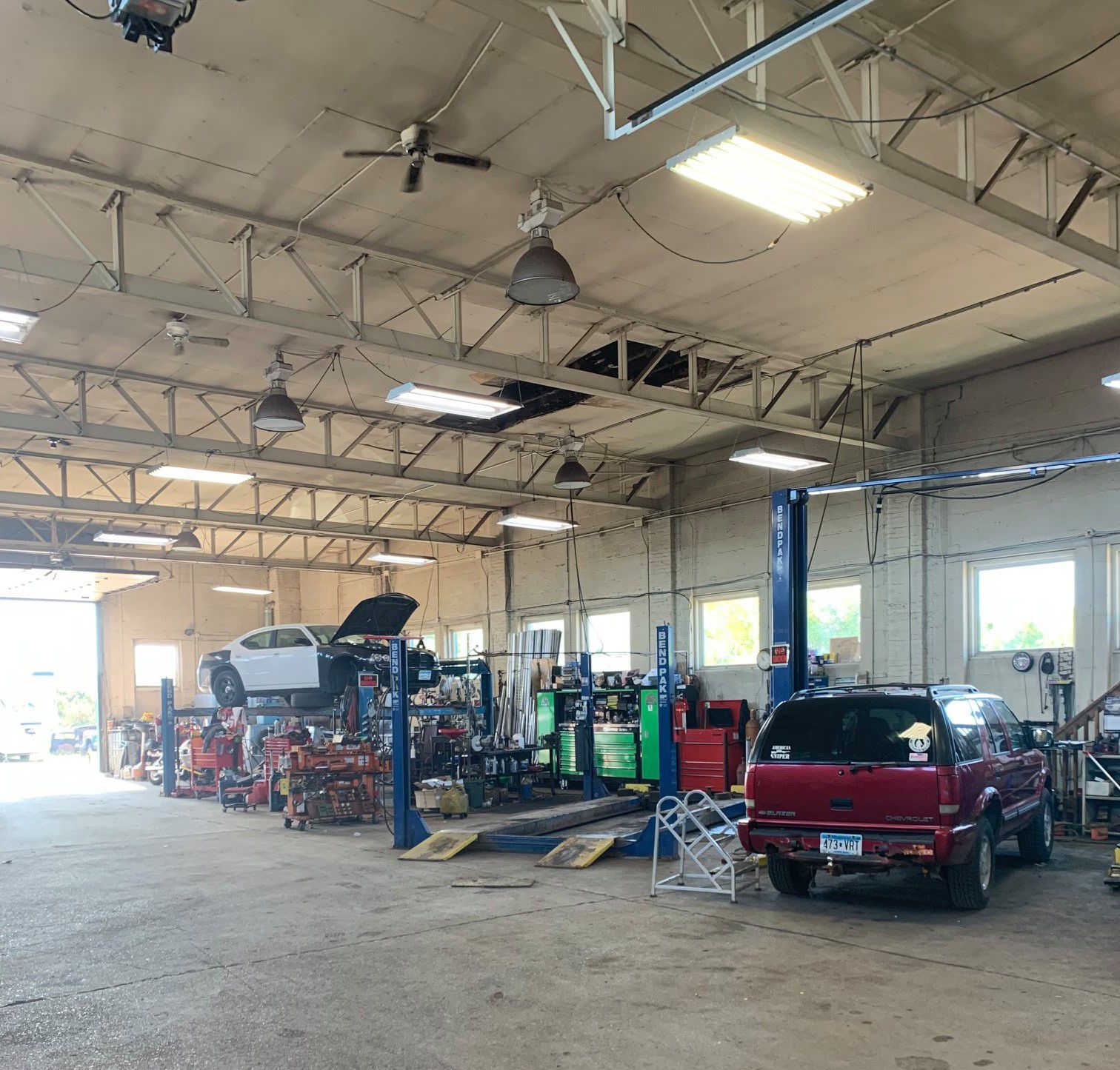 A red suv is parked in a garage with other cars