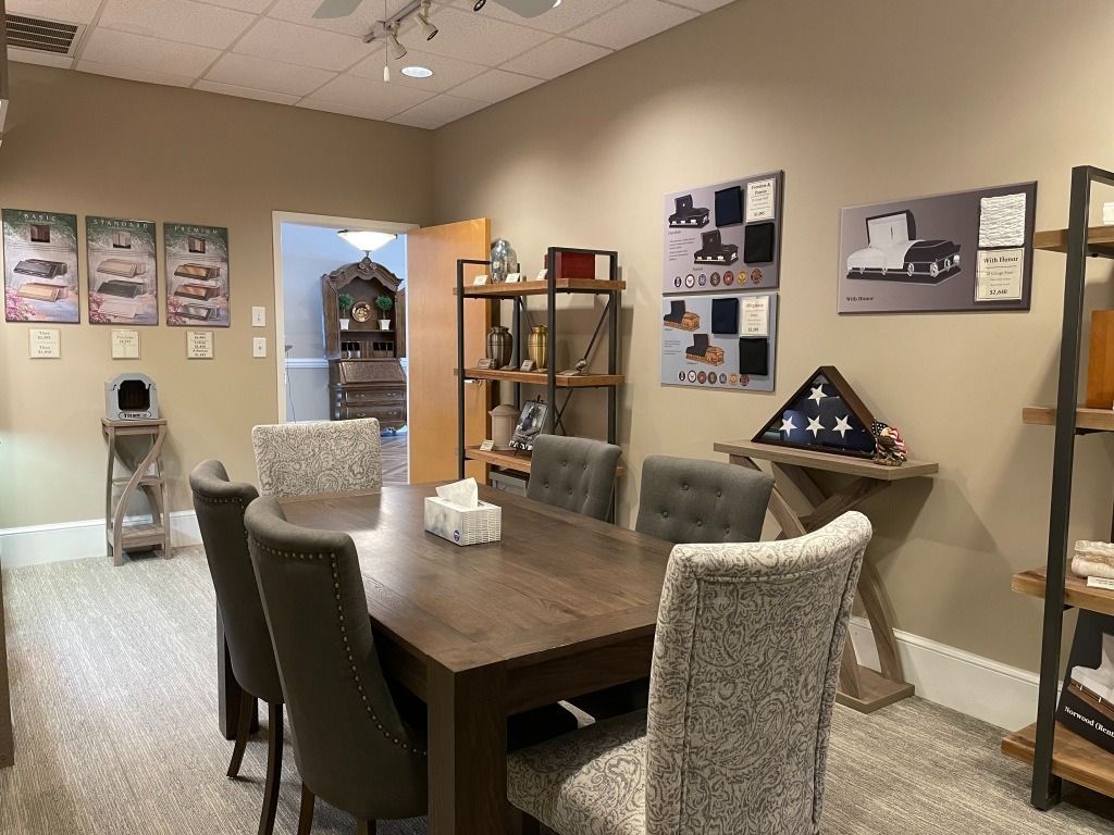 A meeting room with a table, chairs, displays, and an American flag. The room is tan and carpeted.