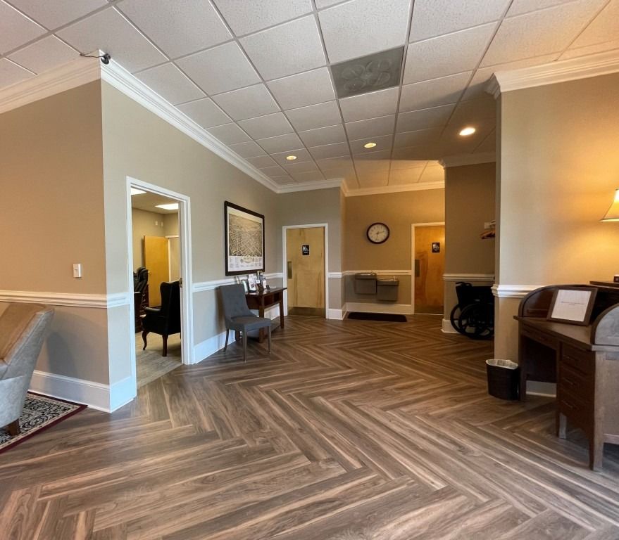 Hallway with herringbone wood-look floor, tan walls, white trim, and doors leading to other rooms.