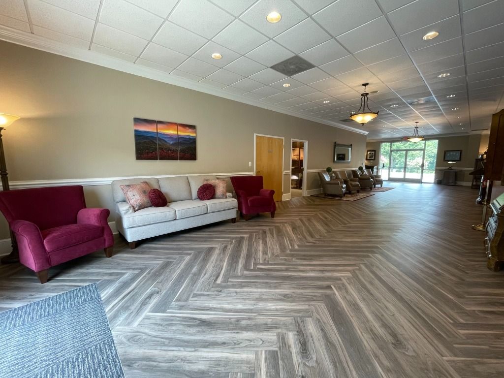 Waiting room with couches, chairs, and wood-patterned floors.